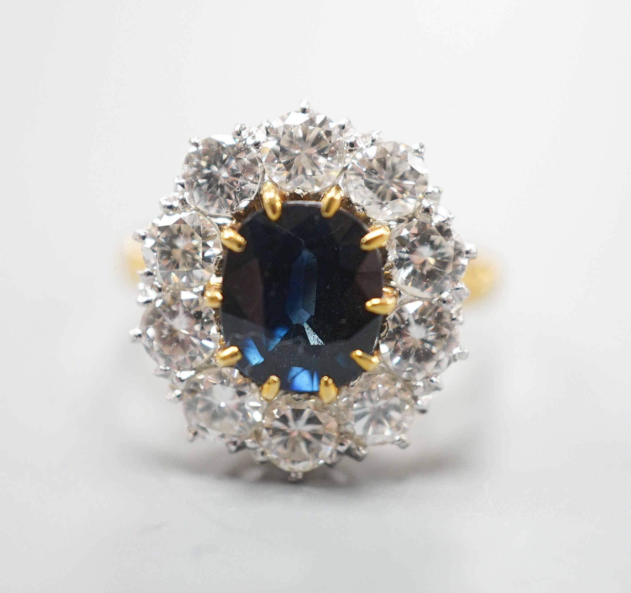 A modern 18ct gold, sapphire and diamond set oval cluster ring, size P/Q, gross weight 6.2 grams.